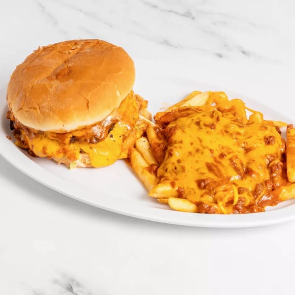 Cheeseburger with melted cheese and chili cheese fries on a white oval plate.