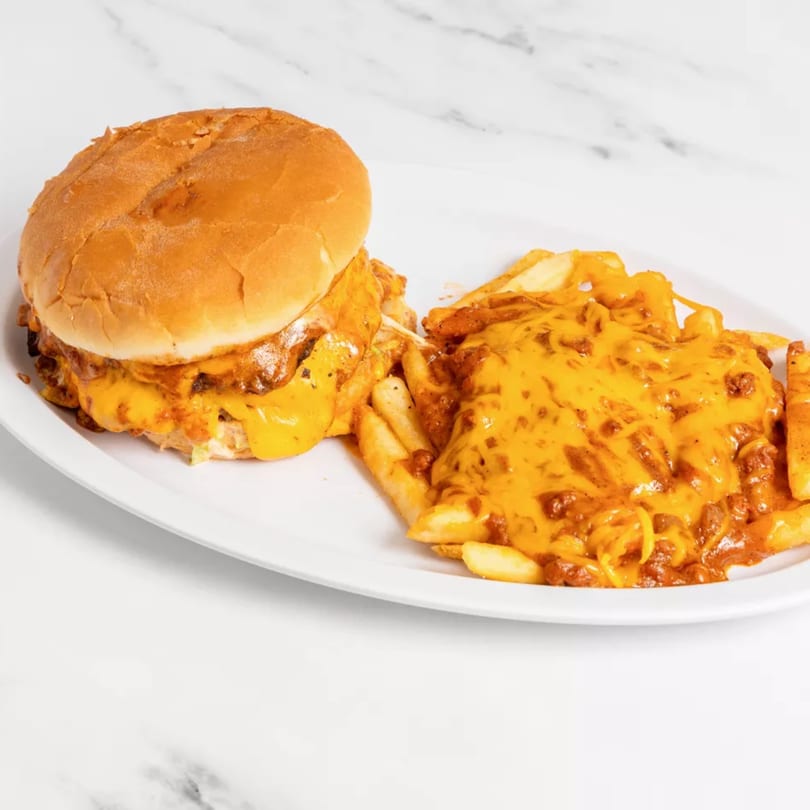 Cheeseburger with melted cheese and chili cheese fries on a white oval plate.